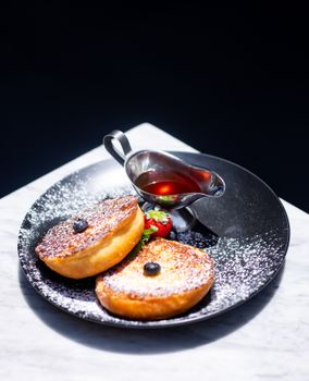 French toast with berries and syrup on a stylish plate, perfect for brunch.