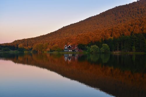 Free Beautiful lake house surrounded by autumn forest reflecting in water. Stock Photo