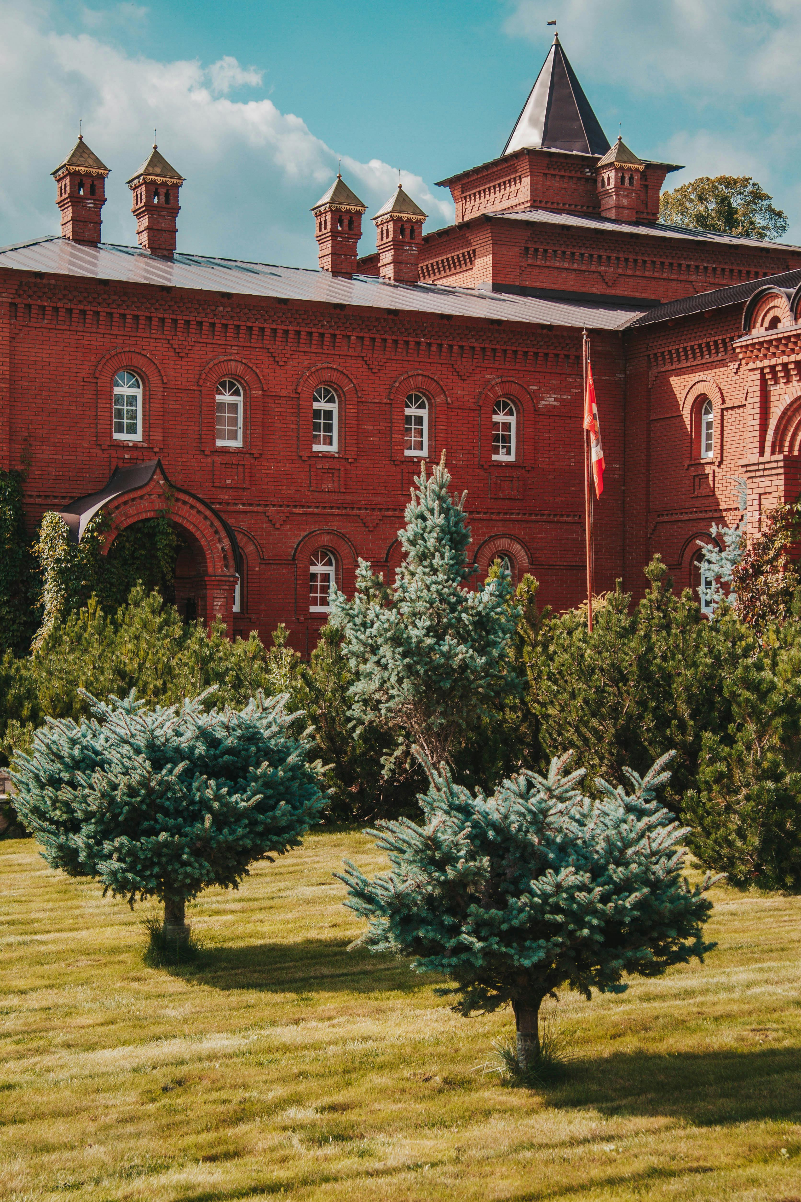 A historic red brick building surrounded by green trees and a well-kept lawn in Bashkortostan, Russia.