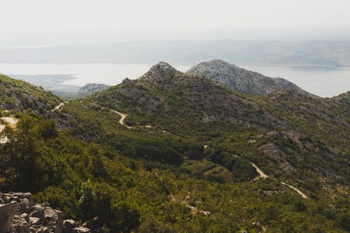 Free Panoramic mountain landscape with a winding path and a tranquil lake in the background. Stock Photo