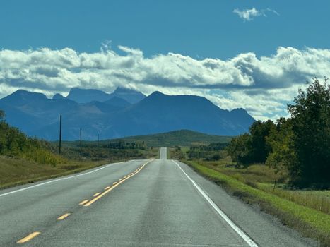 Scenic highway stretches towards distant blue mountains under a vibrant sky, perfect for travel inspiration.