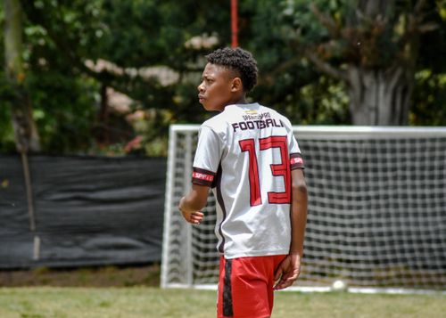 Free Teenager in soccer jersey with number 13 on the field, focused on the game. Stock Photo