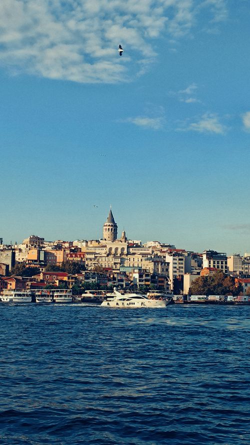 Free Scenic view of the Galata Tower in Istanbul, Turkey, against a vibrant blue sky and calm Bosphorus waters. Stock Photo