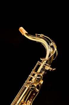 Close-up of a shining gold saxophone on a black background, perfect for music-themed projects.