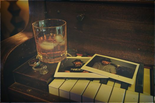 威士忌杯、冰块、复古照片和钢琴上的珠宝共同营造出怀旧的场景