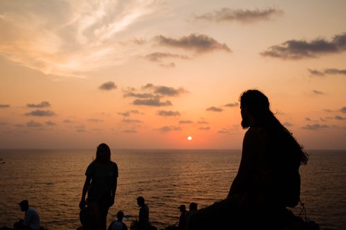 Free Silhouettes of people enjoying a serene sunset over the ocean in Chapora, India. Stock Photo