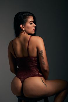 Stylish portrait of an adult woman in burgundy lingerie, elegant pose.