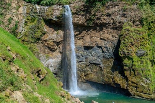 Majestic waterfall cascading over rocky cliffs surrounded by lush greenery.