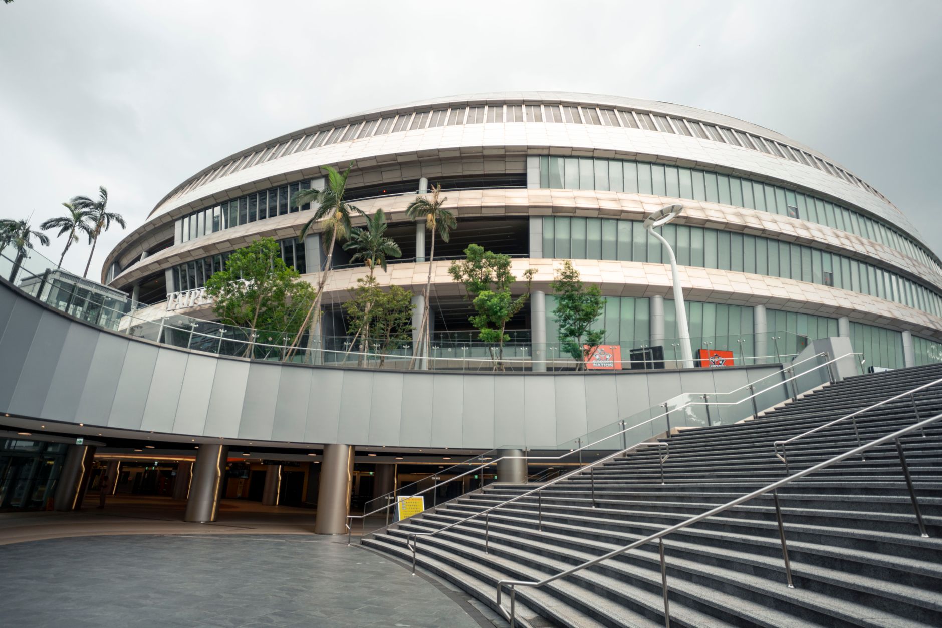 Explore the sleek and modern design of Taipei Arena's exterior, showcasing vibrant landscaping and unique architecture.