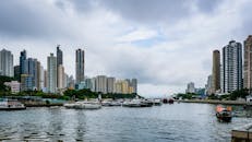 香港港口沿岸，摩天大楼和船只的景色映衬在多云的天空下