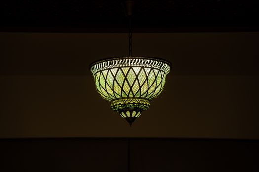 Elegant vintage ceiling light fixture illuminating a dimly lit room with a warm glow.