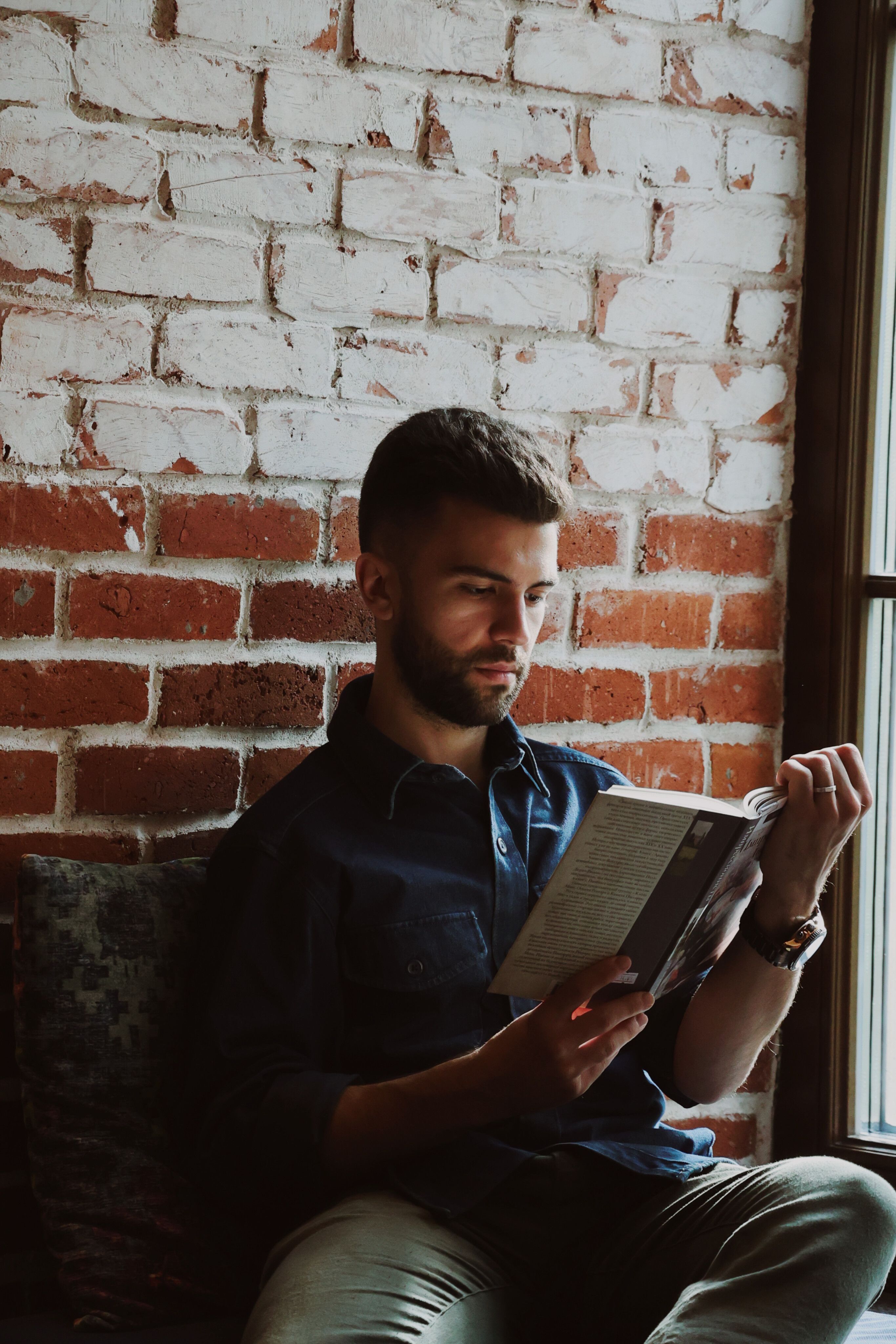 Man Reading by a Brick Wall in Baku · Free Stock Photo