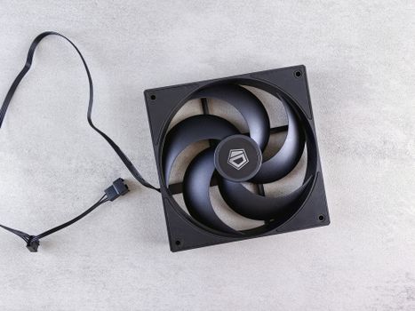 A sleek black computer cooling fan with a cable on a gray textured background.