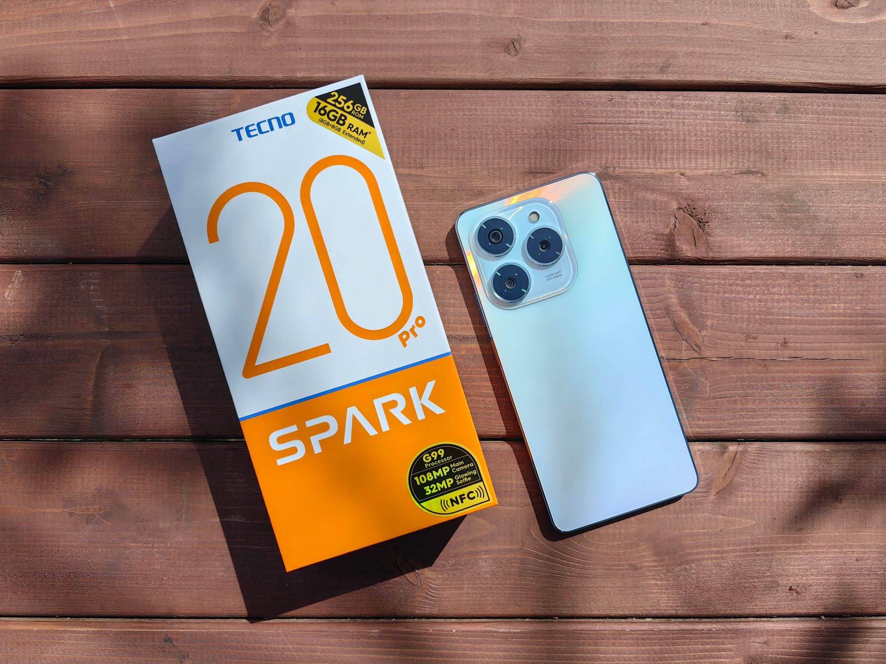 TECNO Spark 20 Pro with packaging on a wooden surface in natural light.