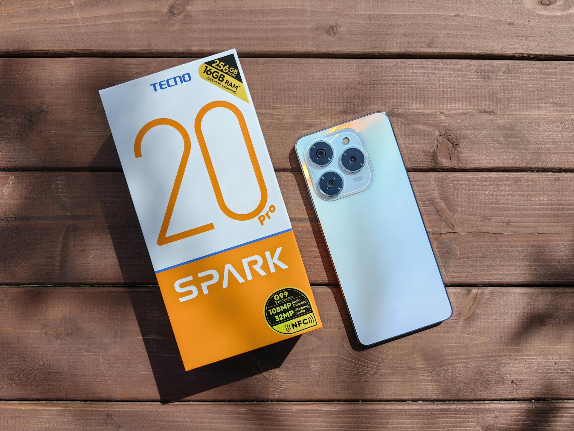 TECNO Spark 20 Pro Smartphone and Packaging on Wooden Surface