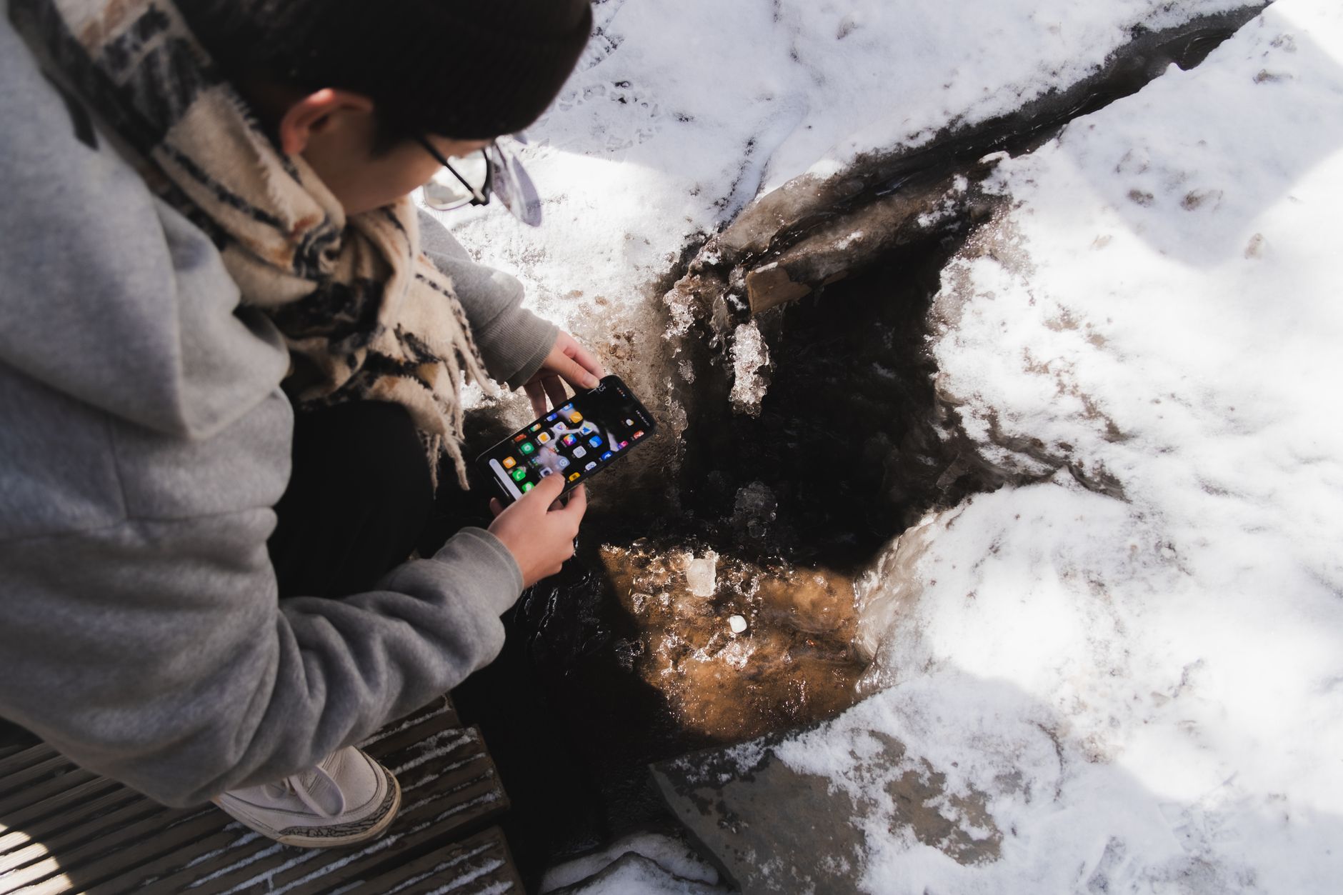 A person placing a phone beside a notebook showing a strict monthly gambling budget and stop-loss limit