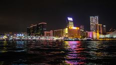 香港的夜空下，天际线灯火璀璨，倒映在水面上