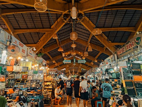Busy indoor market with people shopping under wooden beams.