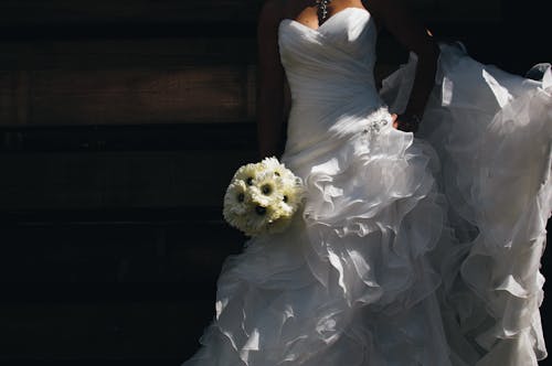 花束を保持している白いウェディングドレスの女性