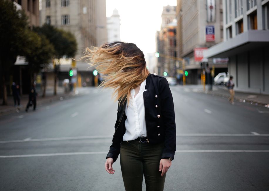 Stylish woman in urban Johannesburg with hair in motion. Fashionable street scene.