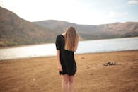 宁静的湖边，一位身穿黑色连衣裙的女子笼罩在夏日的温暖中，景色迷人