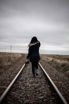 黄昏时分，一名女子独自走在铁轨上，后视镜中的身影传达着孤独与旅程