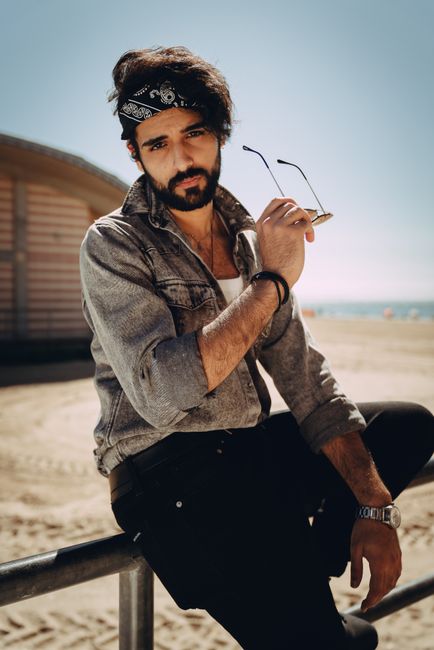Casual portrait of a stylish man with sunglasses on New York beach.