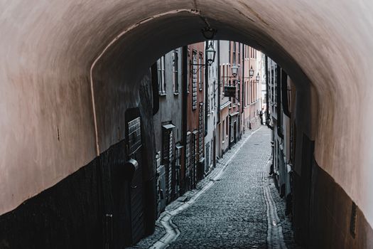 Charming narrow alleyway with cobblestones and archway in Stockholm, perfect for travel and historical imagery.