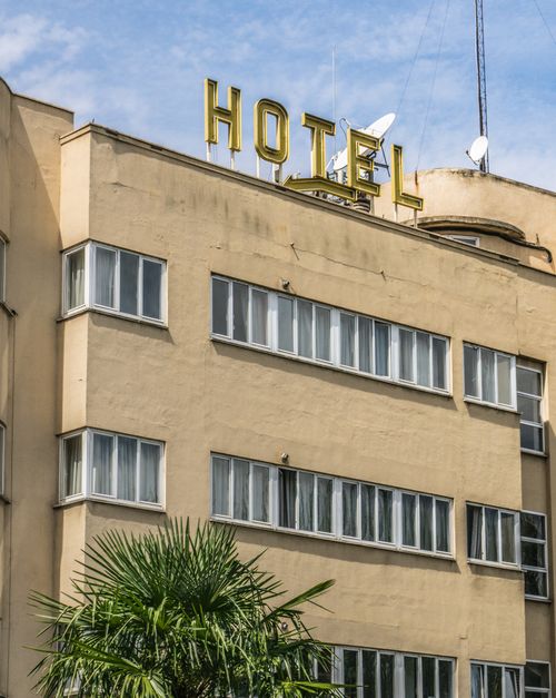 Free Historic hotel exterior with prominent signage and palm tree in urban setting. Stock Photo