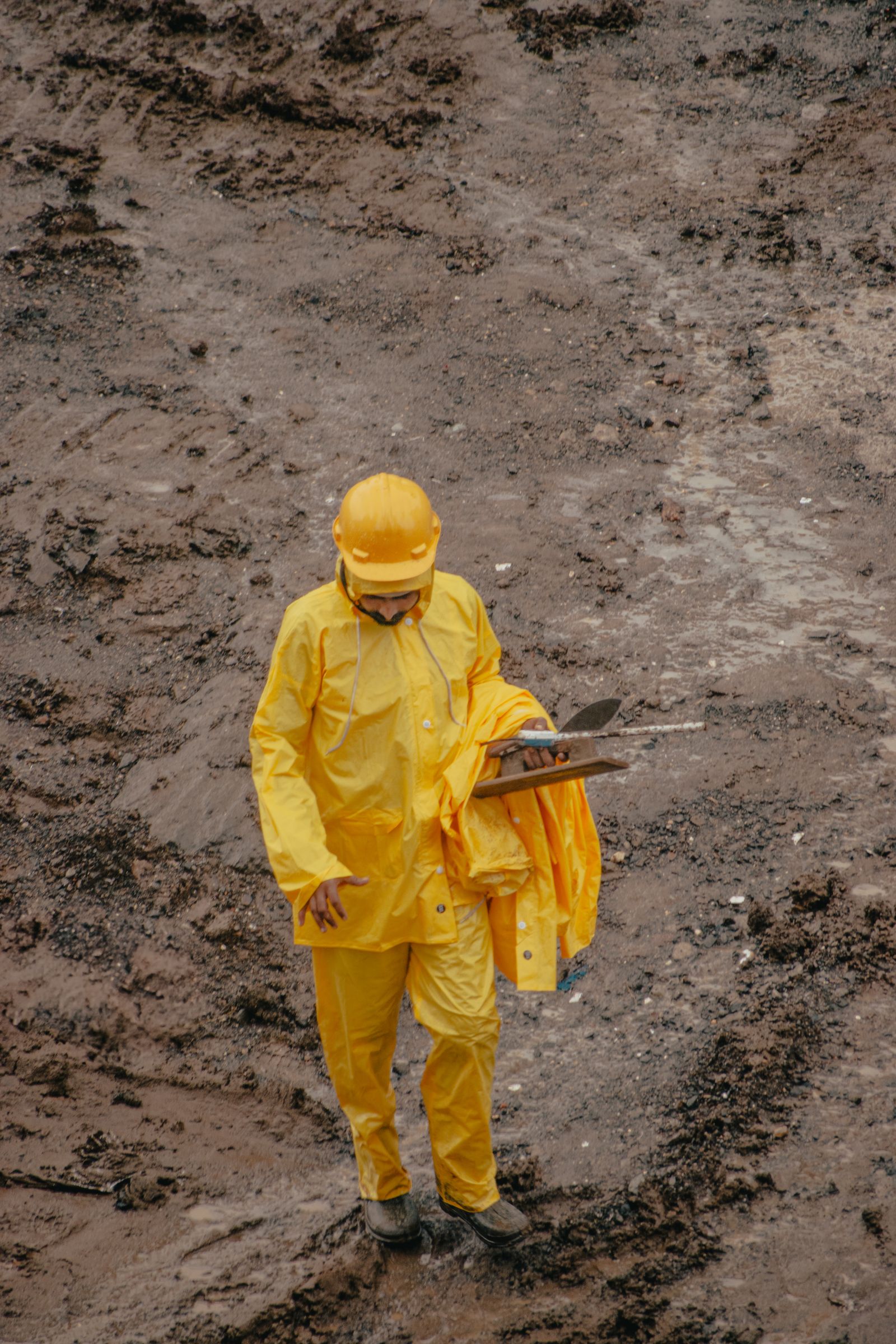 Construction worker in rain gear on a muddy site