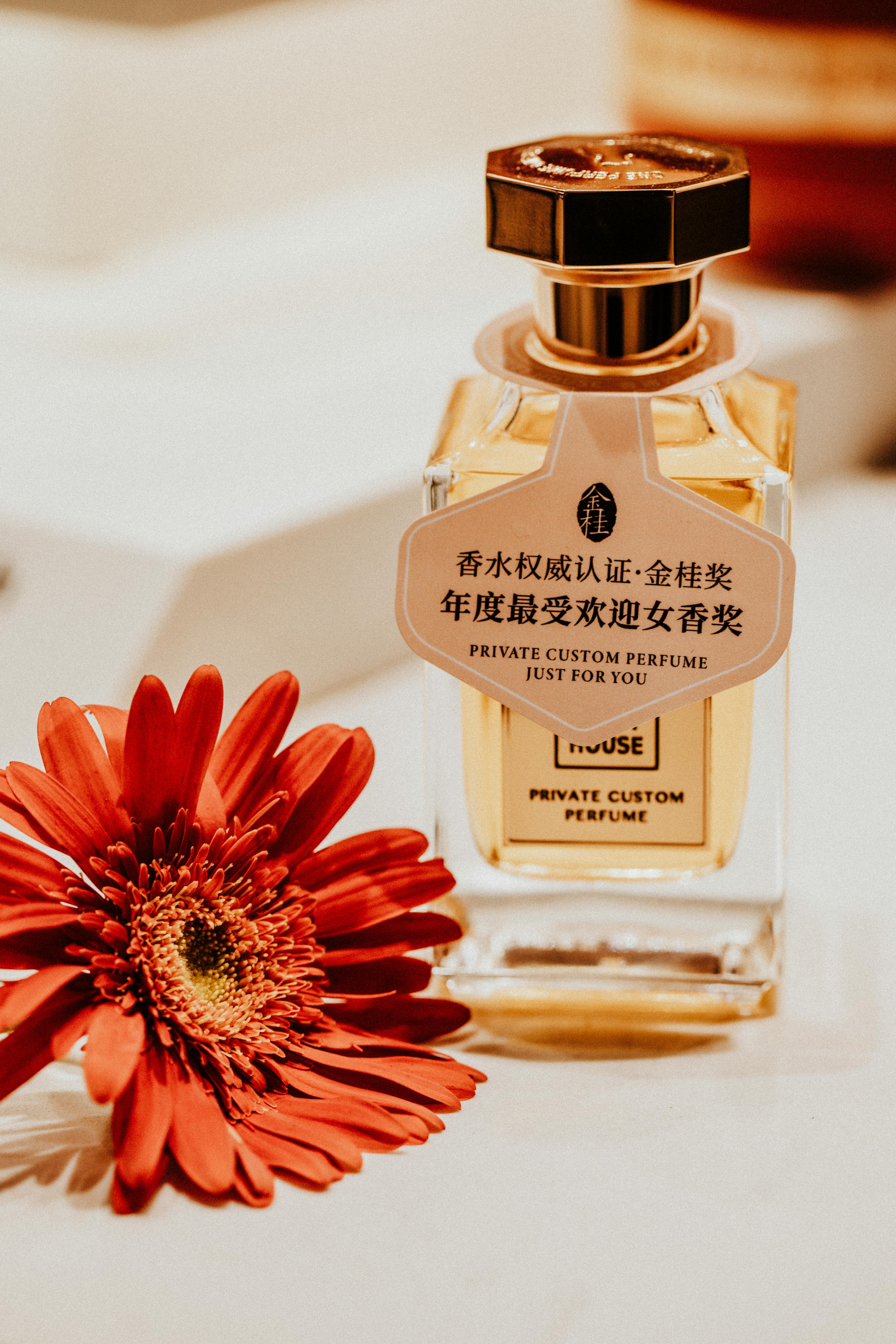 Luxury perfume bottle with vibrant red flower accent, elegant display.