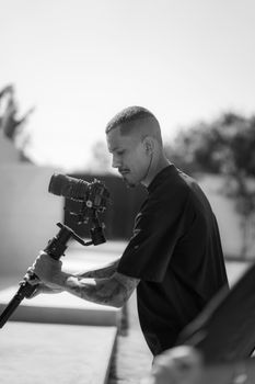 Focused videographer using a stabilized camera outdoors, captured in black and white.