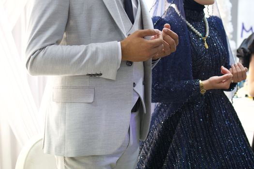 Close-up of bride and groom in elegant attire during wedding ceremony, showing detail.