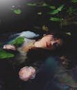 在莫斯科，一位亚洲女子在宁静的水边莲花间摆姿势