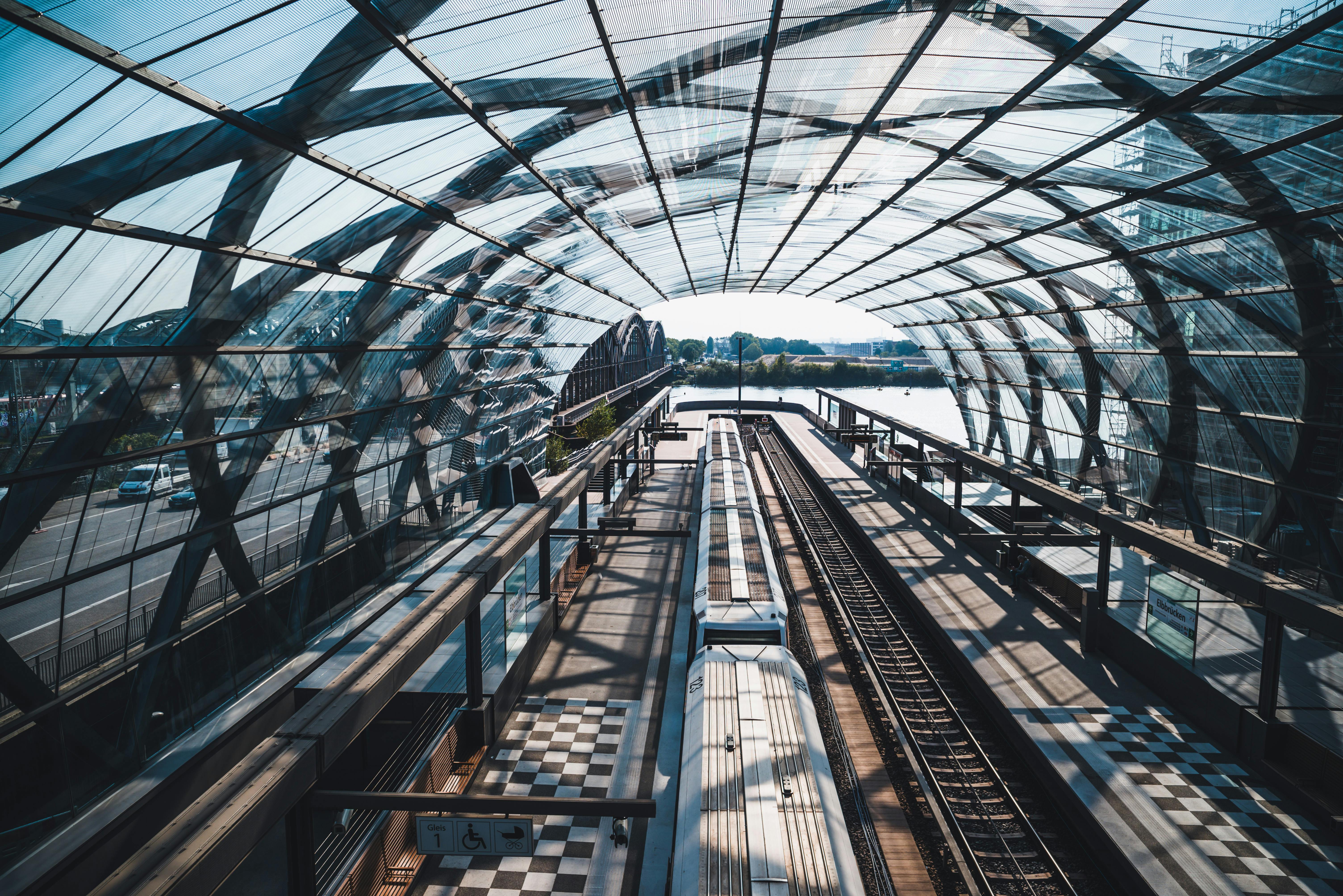 Aerial view of a modern train station in Hamburg, Germany featuring sleek glass architecture with trains on the platform.