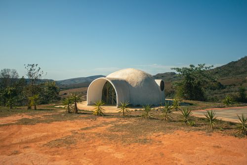 Free A unique dome-shaped house set amidst a tranquil rural landscape under a clear blue sky. Stock Photo