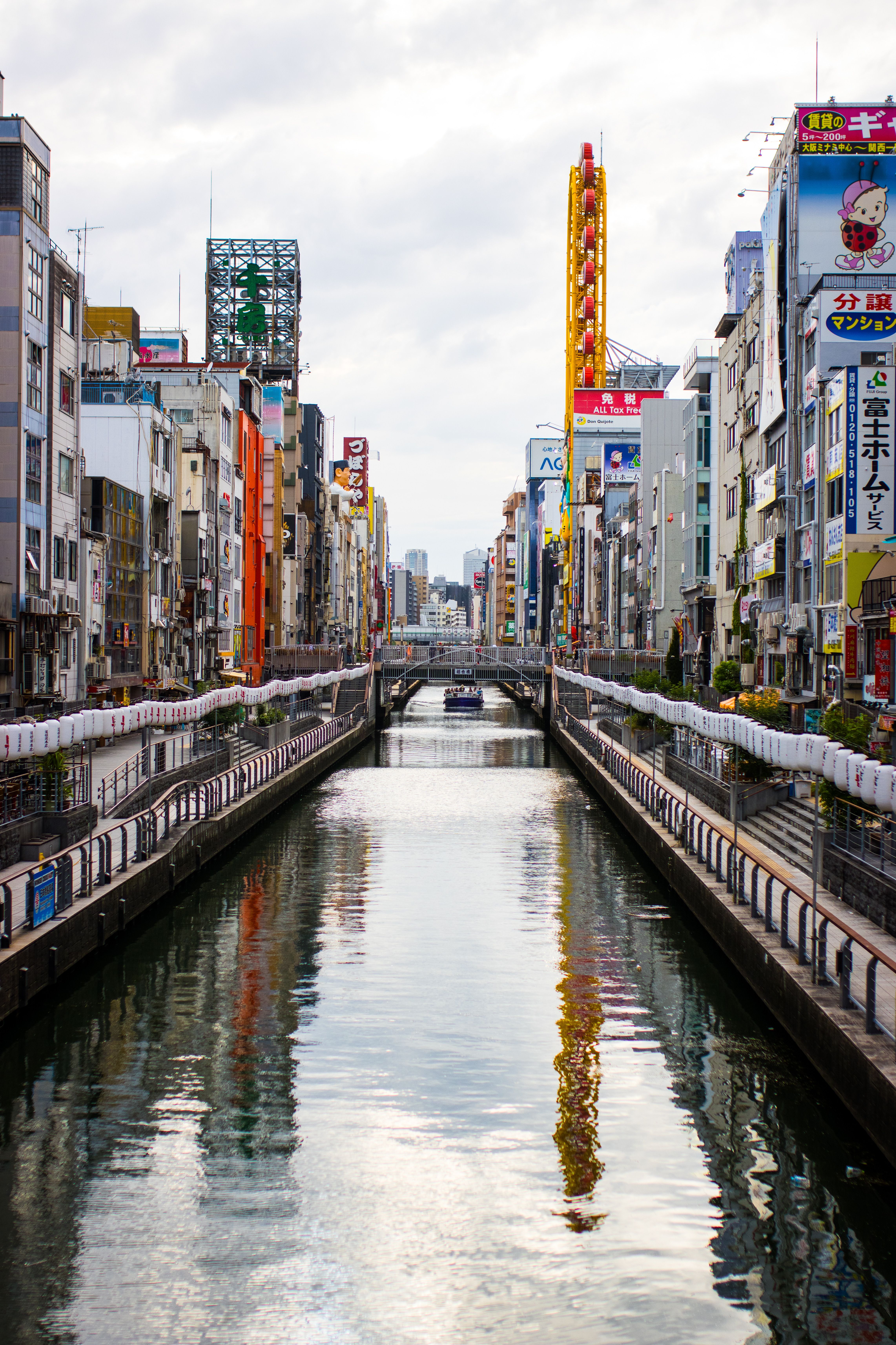 Colorful urban scene of Dotonbori Canal in Osaka with vibrant advertisements lining the streets.