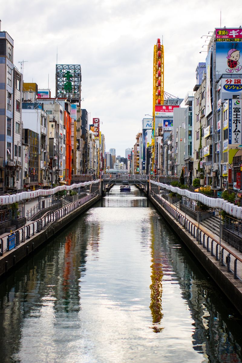 Colorful urban scene of Dotonbori Canal in Osaka with vibrant advertisements lining the streets.