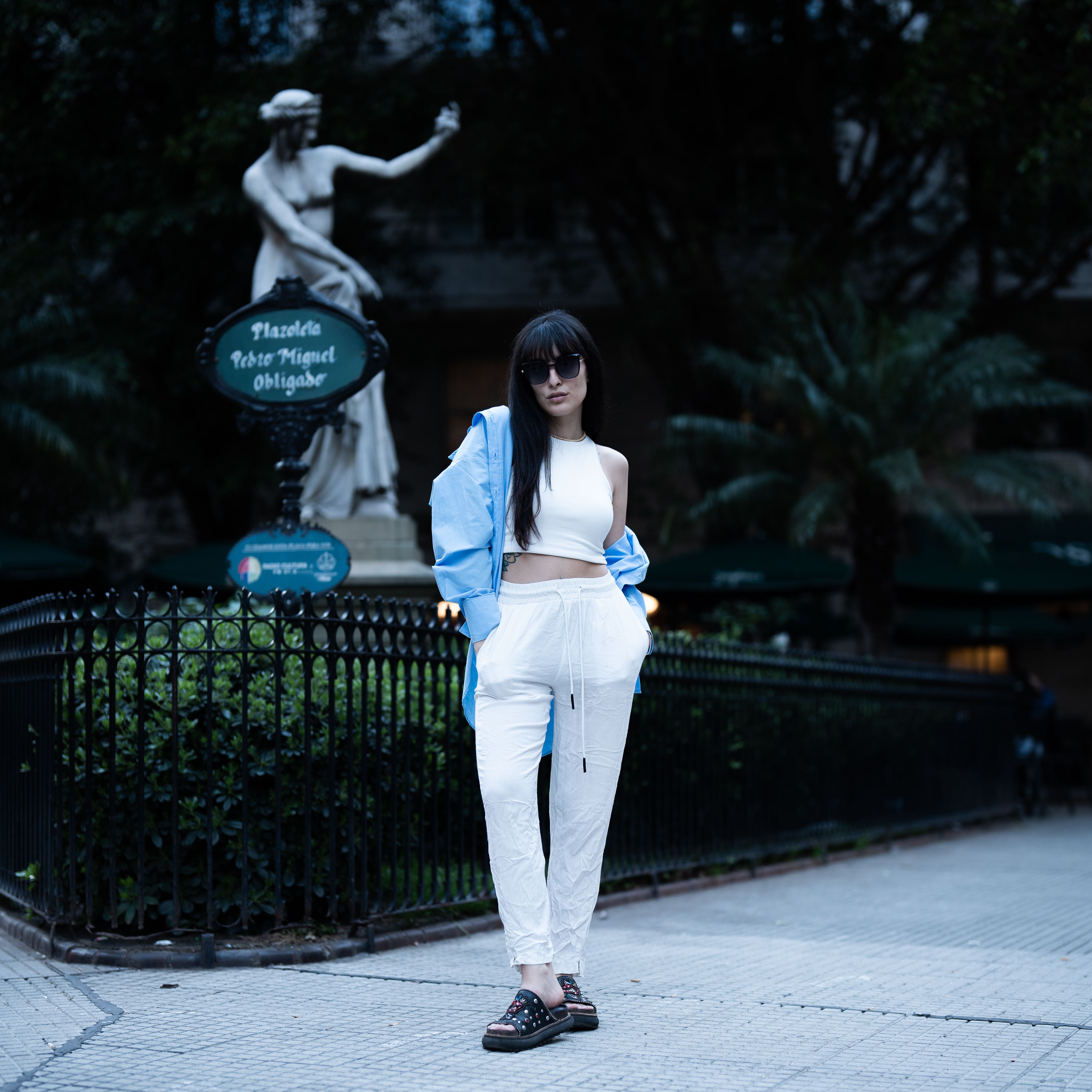 Woman in stylish attire posing in an urban park, exuding confidence and modernity.