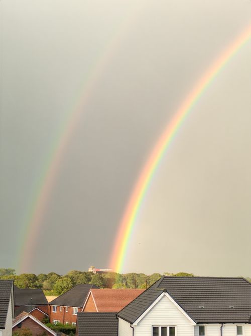 Free A stunning double rainbow arching over suburban houses after rain. Stock Photo