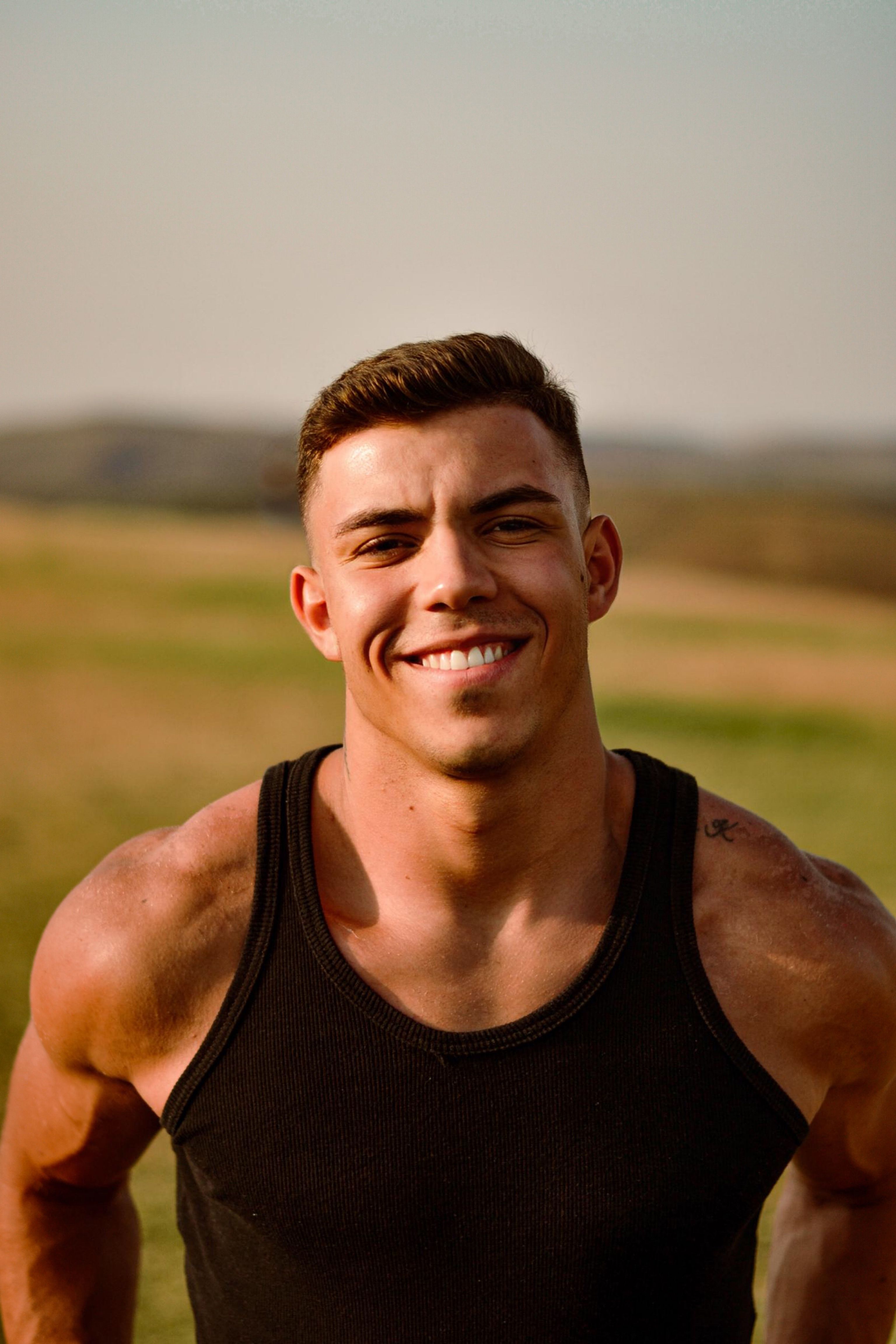 Portrait of a smiling young man wearing a tank top outdoors in Sete Lagoas, Brazil, on a sunny day.