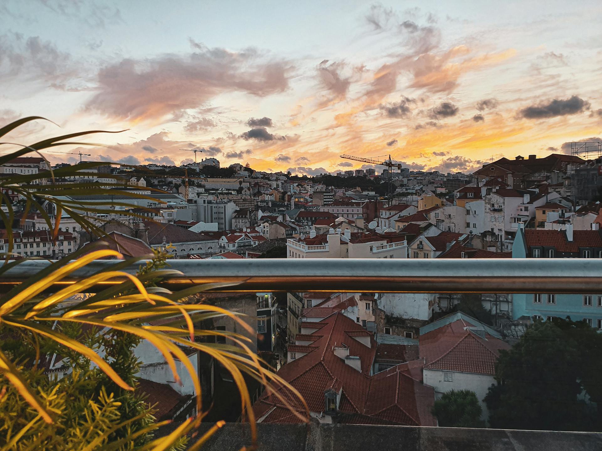 Vibrant cityscape of Lisbon at sunset with picturesque rooftops and colorful sky.