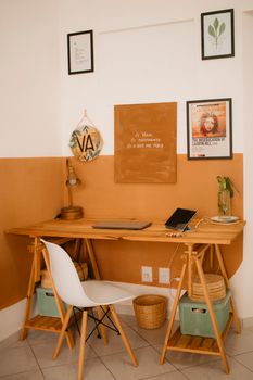 A minimalist home office featuring a wooden desk, chair, and wall art, creating a cozy atmosphere.
