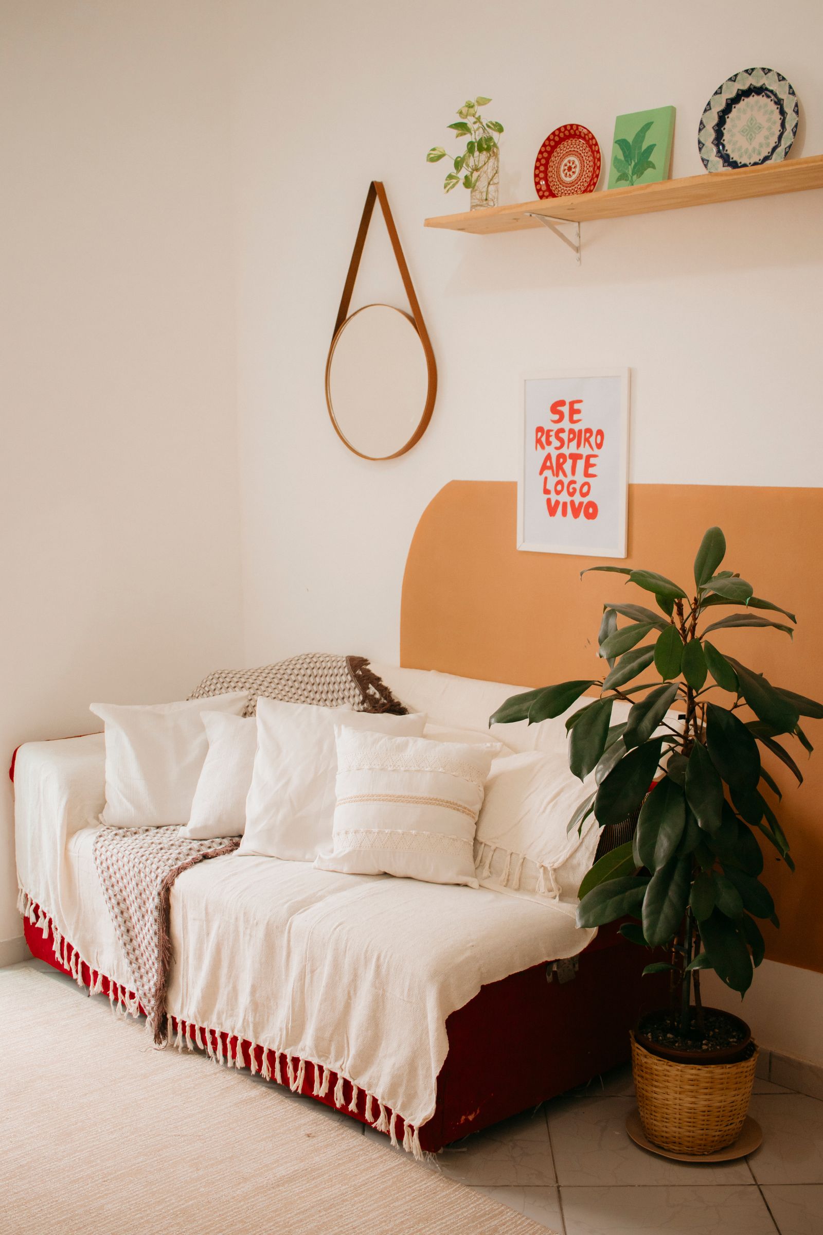 Salon w stylu boho Przytulny salon w stylu boho z kanapą w naturalnej narzucie, rośliną i terakotowym akcentem na ścianie