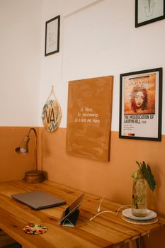 Warm-toned home office space with a wooden desk, laptop, and artistic wall decor.