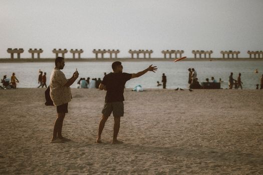 People enjoying a frisbee game at JBR Beach in Dubai during a warm day.