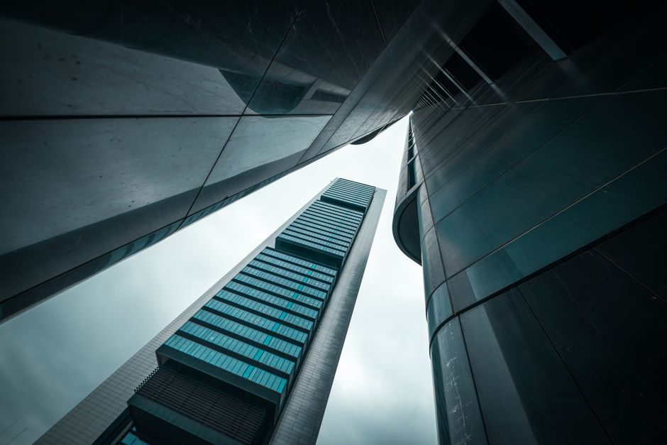 Vista ascendente de rascacielos modernos con un cielo dramático, destacando la arquitectura urbana.