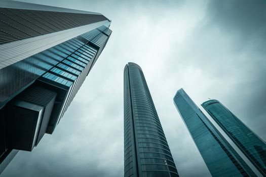 Dramatic view of modern skyscrapers reaching into a clouded sky.