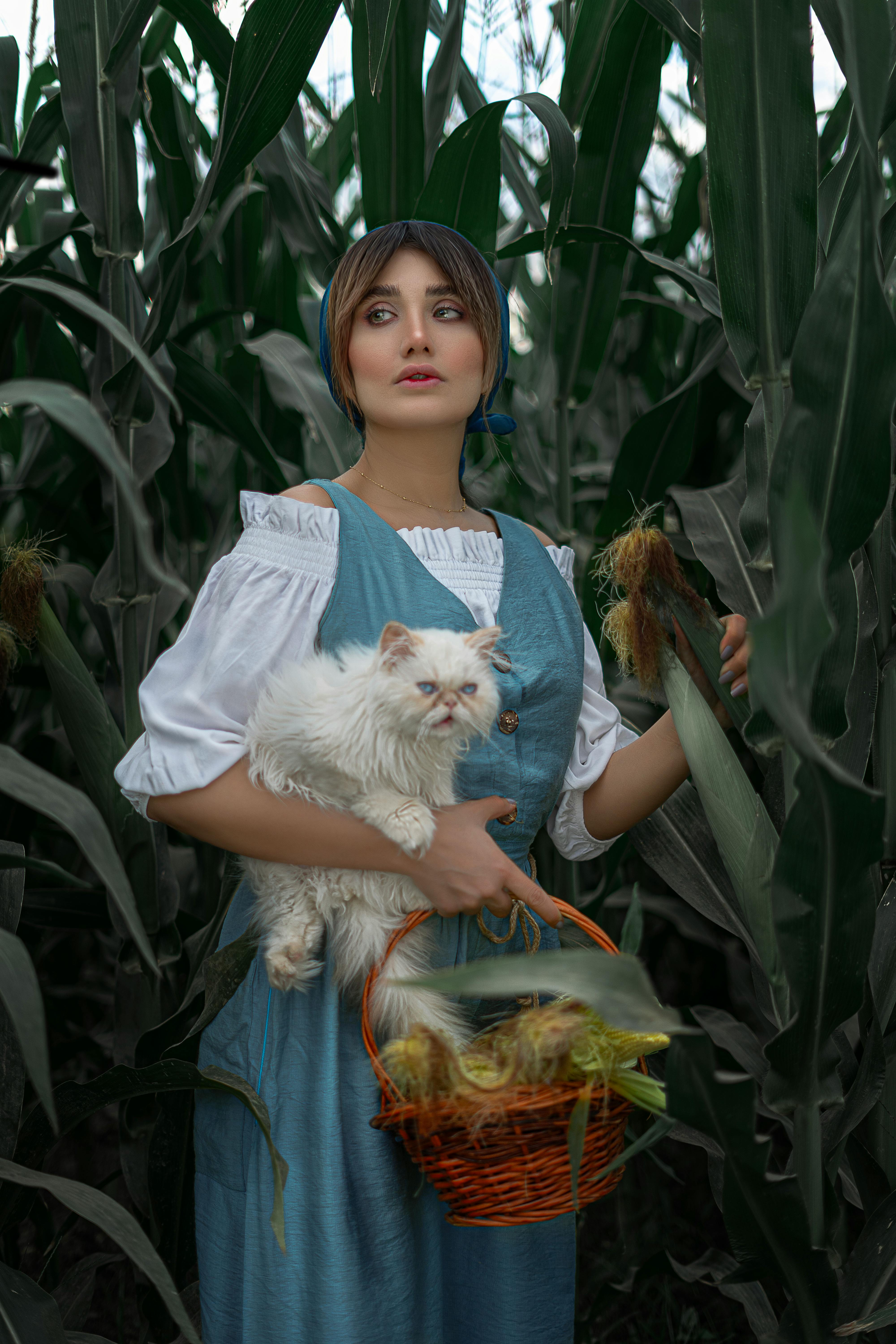 woman in cornfield holding cat and basket