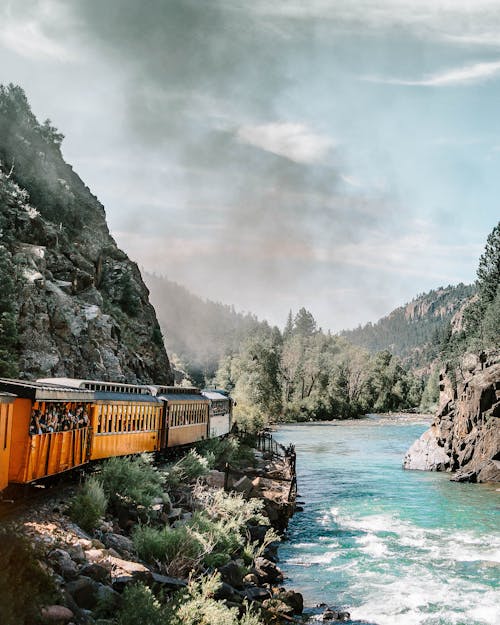 Yellow and Multicolored Train Near Body of Water